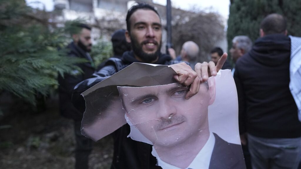 A man tears up a photo of Syrian President Bashar Assad in front of the Syrian embassy in Belgrade, 8 December, 2024